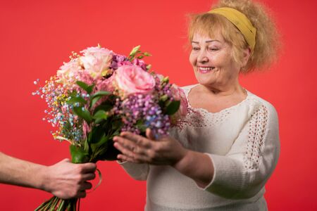 hands of a young woman giving a bouquet of tulips to an elderly woman.march 8, mother's day conceptの写真素材