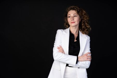Stylish business woman in white suit standing with arms folded, she is calm and confident, black...