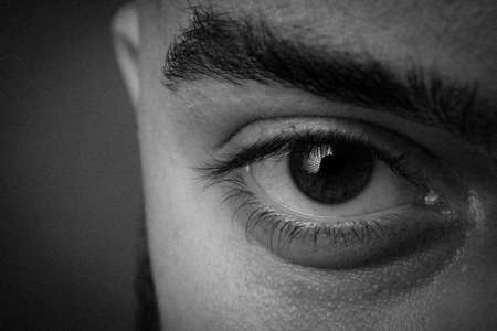 Male eye close up. Black and white photo of the eye. Thick male eyebrows.