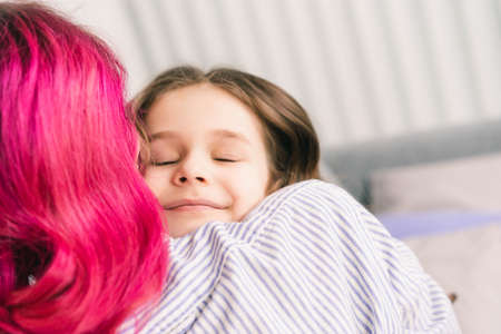 little girl enjoys a strong hug with her motherの写真素材