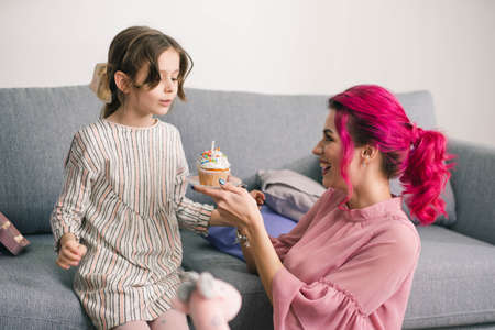 girl blows out a candle on her birthday on a holiday cakeの写真素材