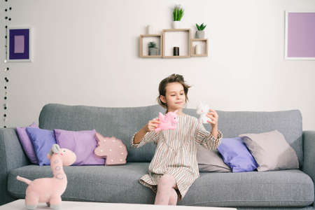 little girl enjoys spending time sitting on toys in her roomの写真素材