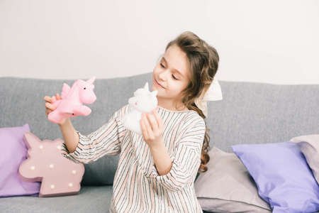 girl intently playing with her toys on the couch with pink pillowsの写真素材