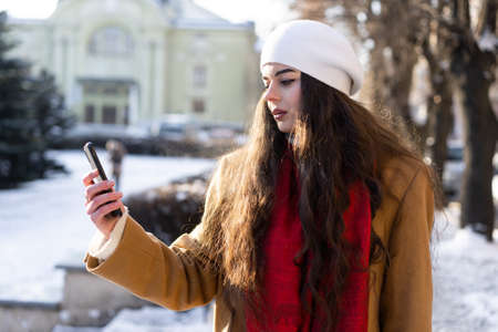 portrait of a young girl who is intently watching the news on her phone while walking around the...