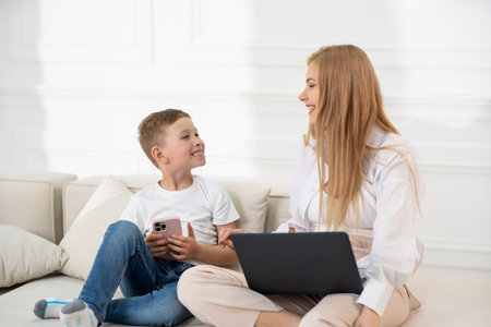 Mom and son laughing at each other sitting on the couch. Family values.の写真素材