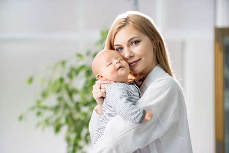 Mom hugs the baby and holds a yogi in her arms. Beautiful woman with a newborn baby.