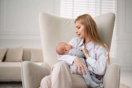 Mom holds the baby in her arms and sits on a chair.の写真素材