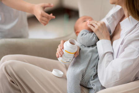 A young mother carefully holds the baby and admires him. Mothers love for her child.