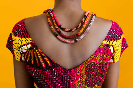A red necklace on black leather, and a red traditional t-shirt. Details of African style on a bright background.の写真素材