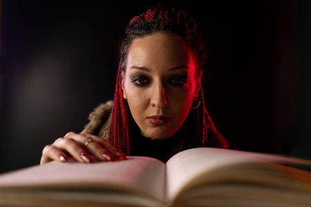 A witch who looks straight into the camera and hypnotizes people. A secret book is opened in front of the witch.の写真素材