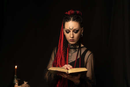 A witch who reads new methods of sorcery in the book. Black magic.の写真素材