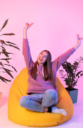 The student is happy to pass the exams. The girl is sitting on a chair and smiling with her hands up.の写真素材