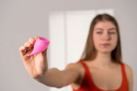 The girl holds a pink menstrual cup in her outstretched hand.の写真素材