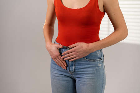 Pain during critical days. Abdominal pain. The girl holds her hands on her stomach.
