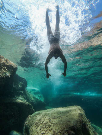 Man diving into the sea. View from inside the water.