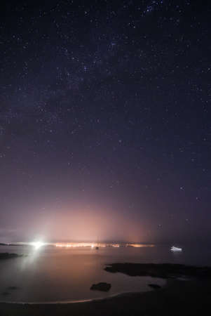 Night seascape on the seashore with starry sky. Vertical framing. Formentera island, Spain.