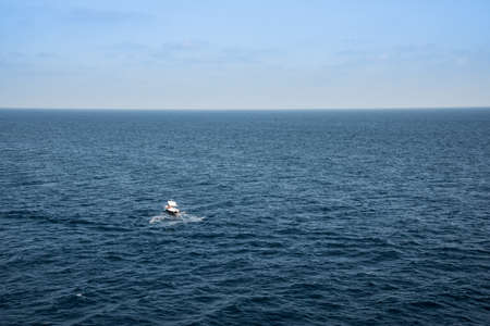 Small boat in the middle of a huge sea on a sunny summer day.の写真素材