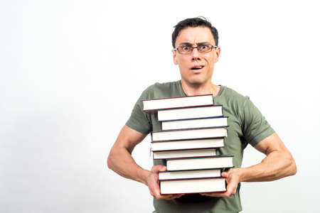 Very worried student with glasses holding a lot of books. Mid shot. White background.の写真素材