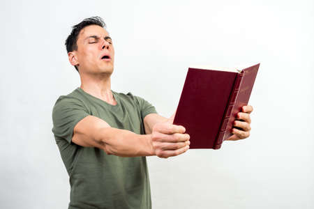 Man spreading a book as far as he can with his arms because he can't see well.の写真素材