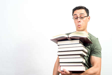 Concentrated man reading while holding a pile of books. Mid shot. White background.の写真素材
