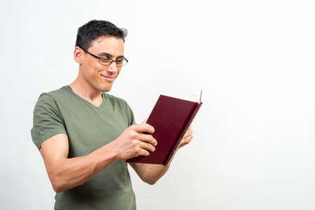 Smiling man with glasses reading a book. Mid shot. White background.の写真素材