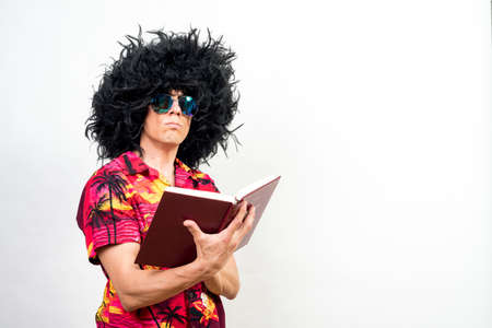 Man with afro wig, sunglasses and hawaiian shirt reading a book. Mid shot. White background.の写真素材