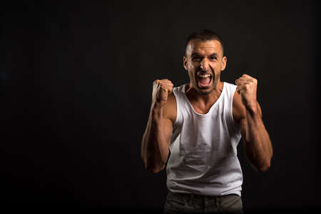 Athlete man in tank top celebrating a victory. Mid shot. Black background.の写真素材
