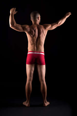 Athletic man in underwear. Full body, back. Black background.の写真素材
