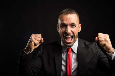 Euphoric man in suit celebrating something. Black background. Close up.の写真素材