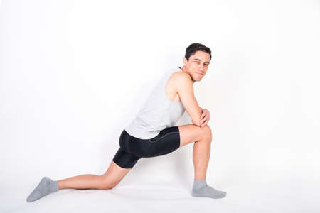 Man in sportswear doing stretching. Full body, white background.