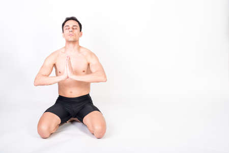 Shirtless athlete man kneeling on the floor, taking deep breaths to concentrate. Full body, white background.の写真素材