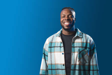 Handsome black man smiling. Mid shot. Blue background