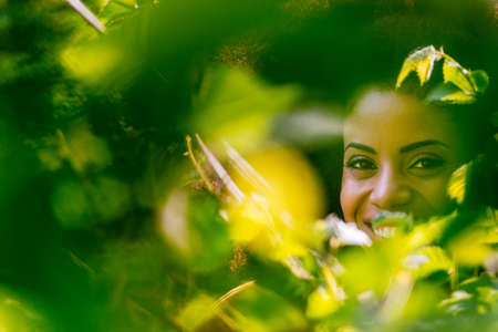Nice portrait of beautiful afro woman through the leaves.