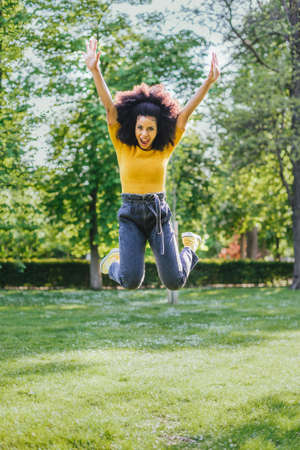 Pretty woman jumping happily in a garden. Full body.の写真素材