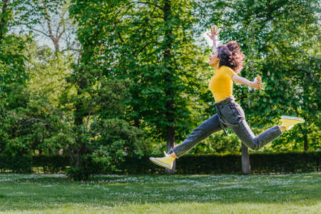Pretty woman jumping happily in a garden.