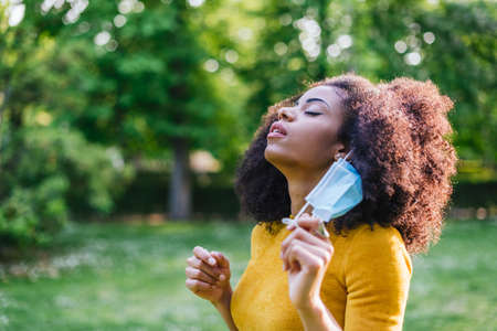 Pretty afro woman, relieved to remove her face mask.の写真素材
