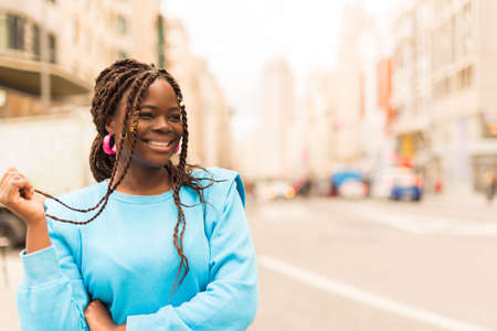 Pretty young black woman smiling in the middle of the city.