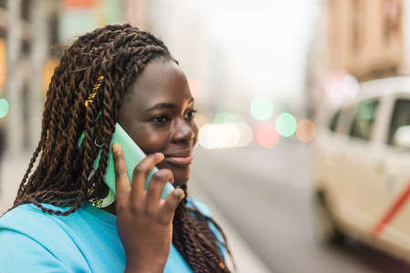Smiling black girl talking on mobile in the city.の写真素材