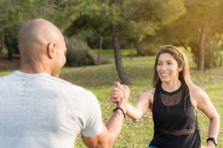 Fitness couple exercising by holding with one hand in the park