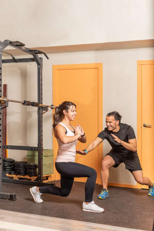 Young woman doing squats without weighting exercise in gymの写真素材