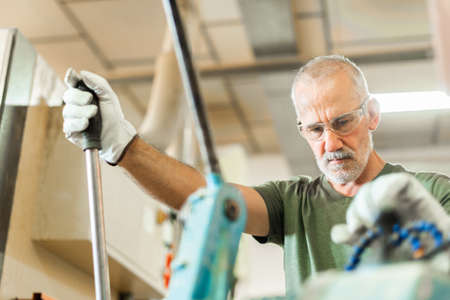 Older worker threading a steel bar in an industrial factoryの写真素材