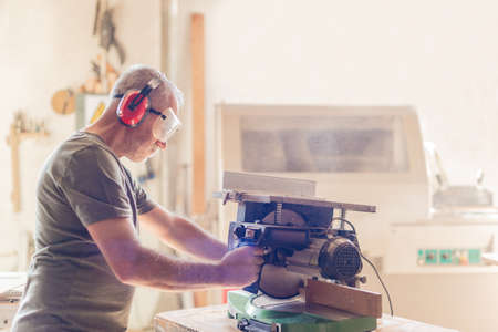 person working with a miter saw in safety equipment