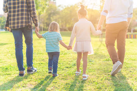 Two children walking hand in hand with their dadsの写真素材