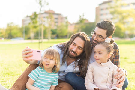 young gay male couple with their children taking a selfieの写真素材