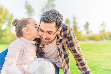 cute little girl kissing her single father in a parkの写真素材