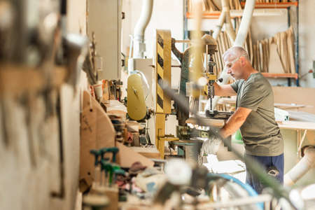 Standing man focused drilling metal in the background