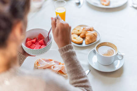View over the shoulder of an unrecognizable woman having breakfast.の写真素材