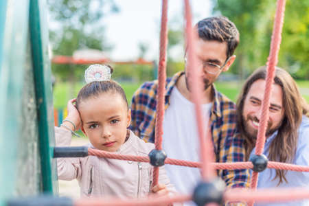 Girl in playground with her parents looking at camera unhappy.の写真素材