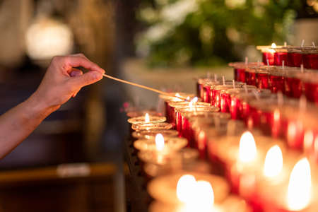 Crop unrecognizable woman lighting candle in churchの写真素材