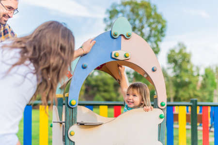 A boy playing in the playground with his adoptive parents.の写真素材